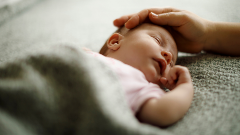Schlafendes Baby wird liebevoll am Kopf gestreichelt – sichere und geborgene Schlafumgebung - Veronika Hilger