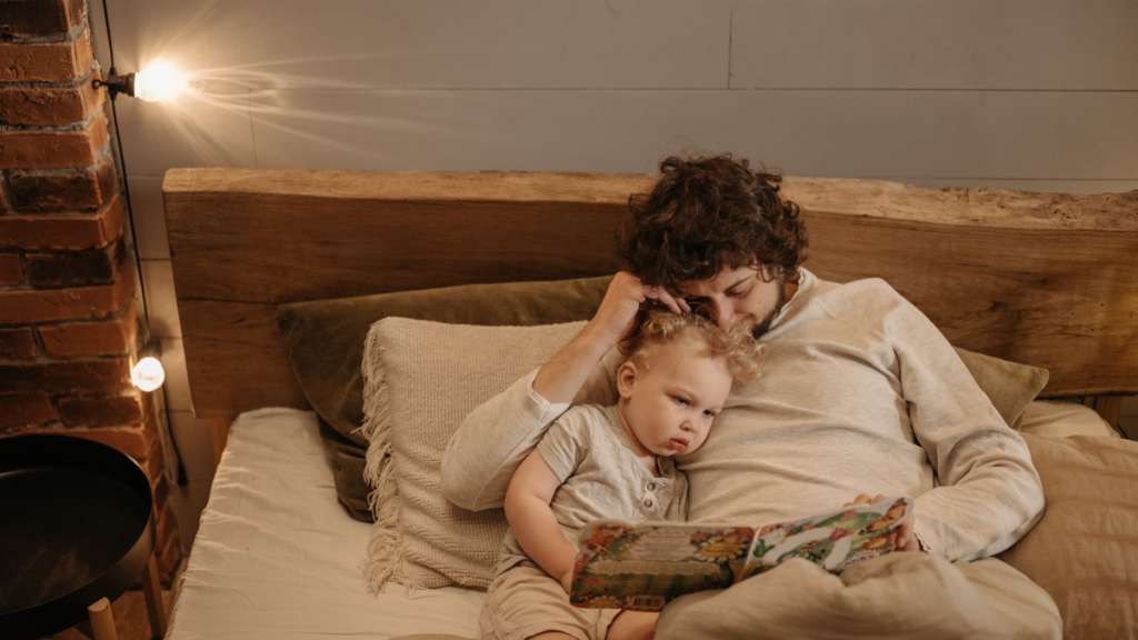Kinderbücher Baby kommt – einfühlsames Vorlesen für werdende GeschwisterkinderVater liest seinem Kleinkind im Bett ein Kinderbuch vor, zur Vorbereitung auf ein neues Baby. - Veronika Hilger BE GOOD TOGETHER