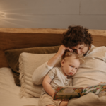 Kinderbücher Baby kommt – einfühlsames Vorlesen für werdende GeschwisterkinderVater liest seinem Kleinkind im Bett ein Kinderbuch vor, zur Vorbereitung auf ein neues Baby. - Veronika Hilger BE GOOD TOGETHER
