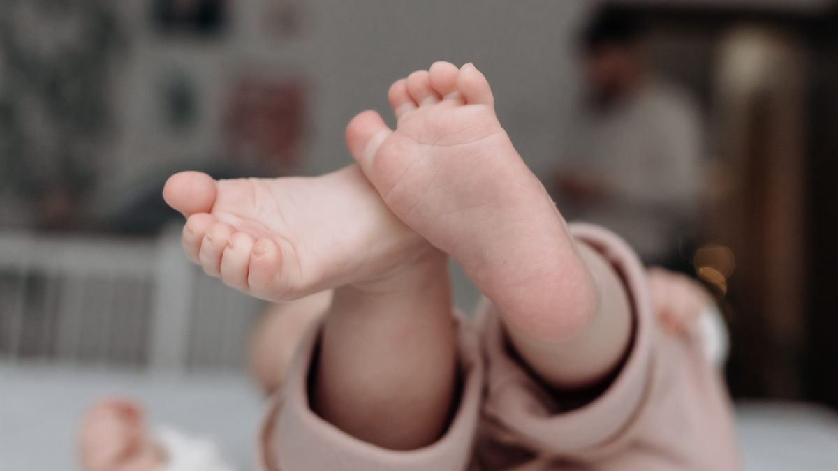 Barfußfüße eines Babys in gemütlicher Kleidung, entspannt auf dem Rücken liegend - Veronika Hilger