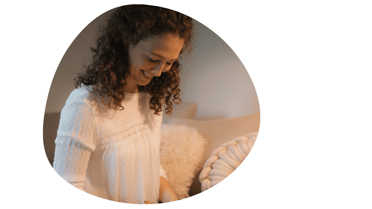 Lächelnde Frau, Veronika Hilger, in heller Bluse sitzt entspannt auf einem Sofa und wirkt liebevoll und fürsorglich – Symbol für persönliche Betreuung und ganzheitliche Begleitung im Wochenbett.