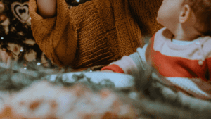 Mutter hält Neugeborenes im Arm vor weihnachtlicher Deko während der Adventszeit. Advent mit Neugeborenem